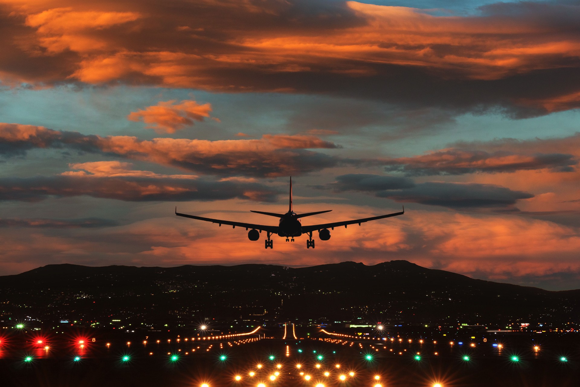 Sunset Landing: Airplane Approaching Runway Amidst Fiery Skies